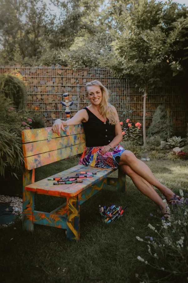 Kateřina Hampel na pomalované lavičce v zahradě